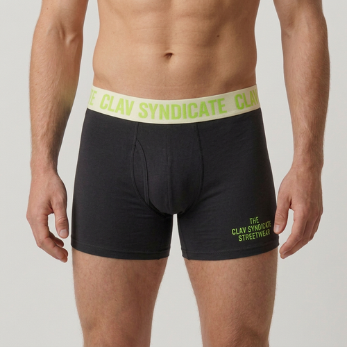 Närbild på charcoal/svarta C.L.A.V Syndicate-boxers med cremevit linning och neongrön text